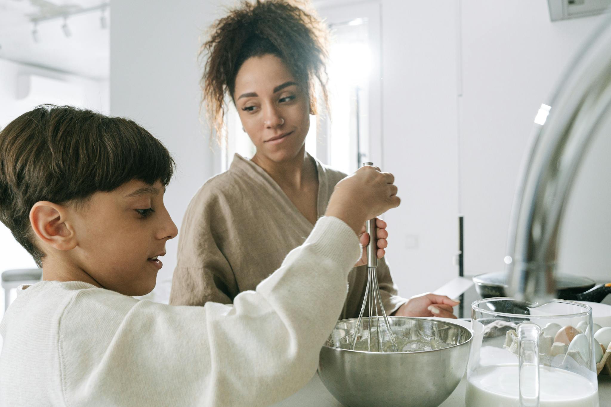 Mother and son enjoying quality time baking together in a cozy home kitchen.