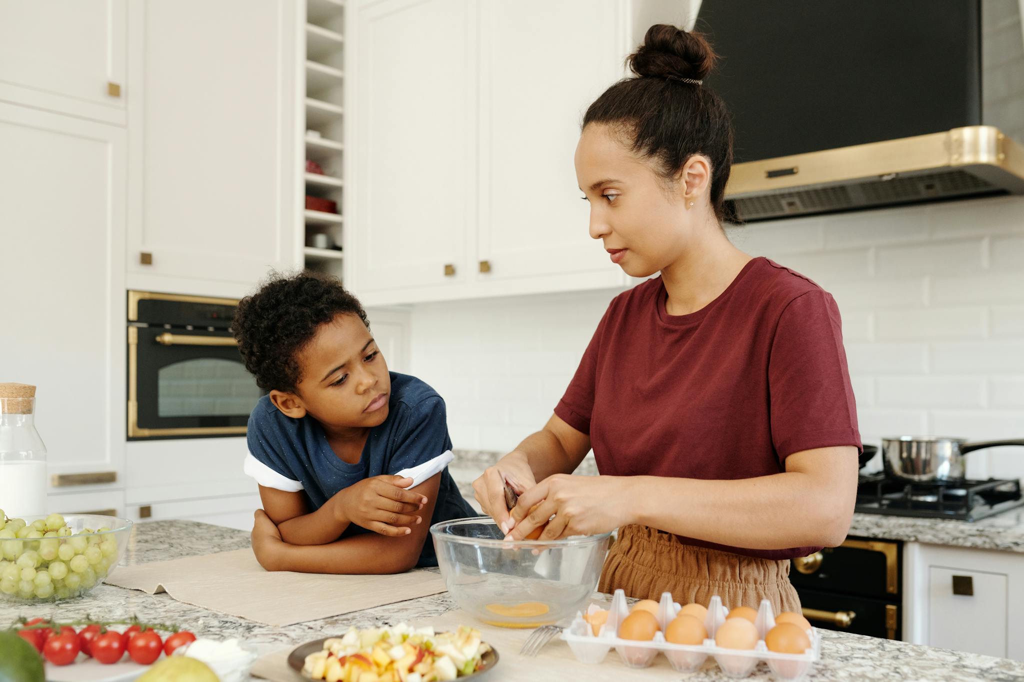 Mother and son enjoying quality time preparing food in a modern kitchen setting.